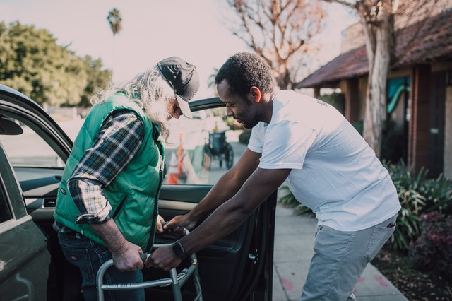 man helping another man use a walker